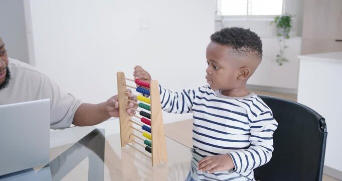 African American father noticing preschool son, guiding while son moving abacus at home with laptop