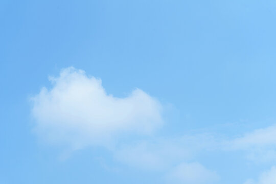 White fluffy cloud on clear blue sky background. Clean minimalist sky background with copy space for text or design.