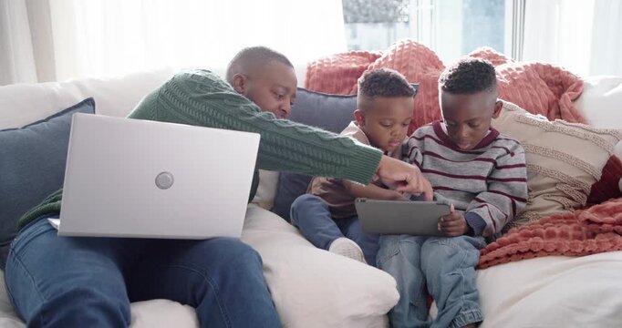 African American father with two sons reaching and pointing while guiding tablet use on couch