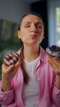 Woman with eating disorder eating two donuts with pleasure and at the same time