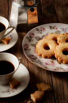 Coffee cups, moka pot and flower-shaped cookies on a rustic wooden table