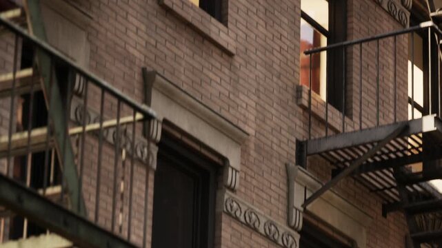 Metal fire escapes extend from a residential brick building, showcasing traditional city architecture and vintage structural design in the neighborhood.