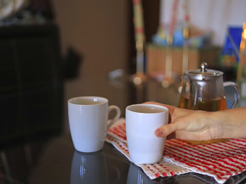 Hand holding a white mug, food and beverage service with ceramic drinkware for a tea break in a home kitchen.