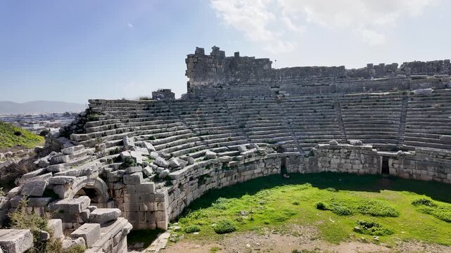Xanthos ancient theater in Lycia near Kas, Antalya, Turkey, curved stone seating rows around a grassy orchestra among the ruins of the Lycian city