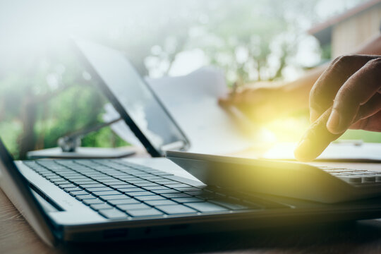 Businessman using calculator with laptop and financial documents in outdoor natural light setting, concept of business accounting, budget planning, and remote office productivity.