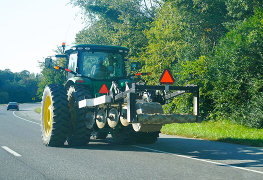 Milton, Delaware, U.S.A - Oct 14, 2026 - A green John Deere tractor equipped with heavy soil cultivation machinery driving along the road edge on Route 1