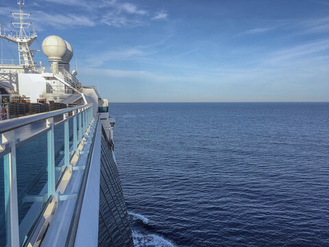 Pooldeck or swimmingpool with sun deck on modern cruiseship cruise ship liner in port with sun loungers ready for cruising to Mediterranean on sunny day with city skyline in background