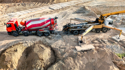 At a construction site, a concrete pump and mixer truck pour concrete into the foundation during site work © Anoo