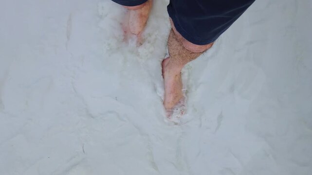 Pamukkale, Denizli, Turkey, close-up from above of a man's bare feet walking on the white travertine terraces, where visitors must walk barefoot