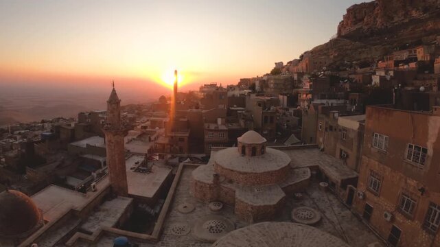 Mardin old town, Turkey, at sunset, sandstone houses, minarets and domes stepping down the hillside below the castle rock, overlooking the Mesopotamian plain