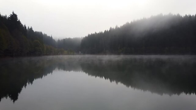 Karagol lake in Savsat, Artvin, Turkey, on a foggy autumn morning, dense mist drifting across the forested hills and mirrored in the glassy surface of the lake