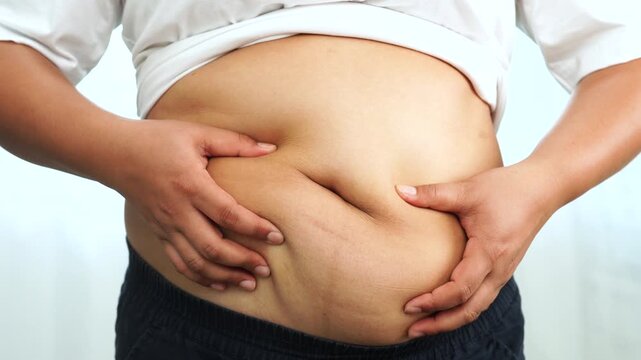 Asian woman use hand to squeeze fat belly big size overweight and obesity.