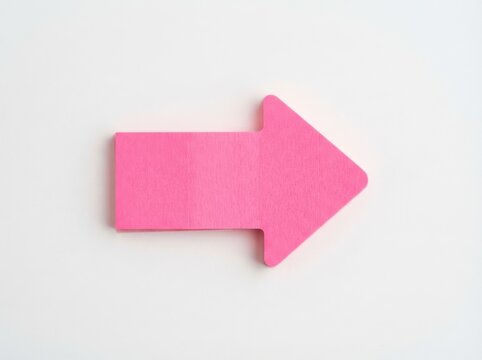 Pink sticky note arrow pointing right on a white background with soft studio lighting