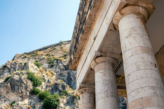 Stone columns of Agios Georgios church beside Old Fortress slopes, Corfu, Greece, summer sky