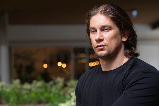 Urban lifestyle shot of a tired and sleepy caucasian man in his 30s outdoors, pausing for a moment of relaxation amidst small city garden