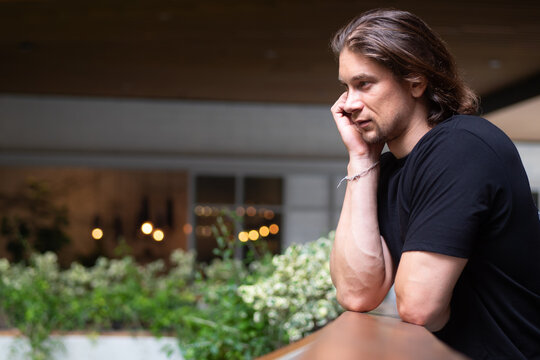 30s caucasian man in casual clothing thinking alone in an indoor garden