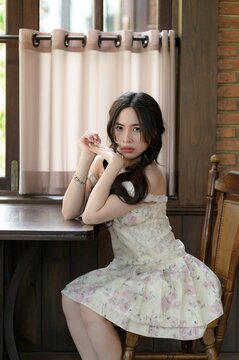 Young woman sitting at wooden table in cozy room with natural light