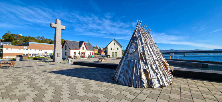 Gasp&eacute;, Canada - October 1, 2026: The Jacques Cartier granite cross, historical buildings, and a traditional Mi'gmaq wigwam at the Cradle of Canada site (Berceau du Canada) in Gaspesie, Quebec.