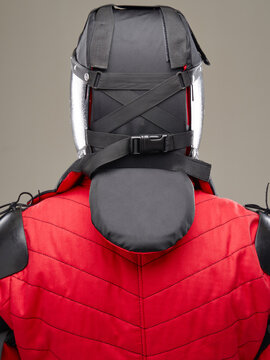 Rear view of HEMA helmet with straps and padded protection worn over red gambeson.