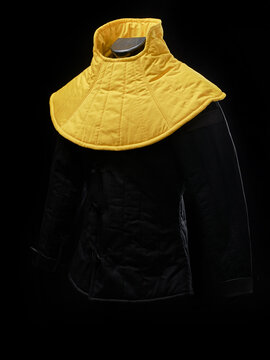 Yellow padded HEMA gorget displayed on black jacket over dark background.