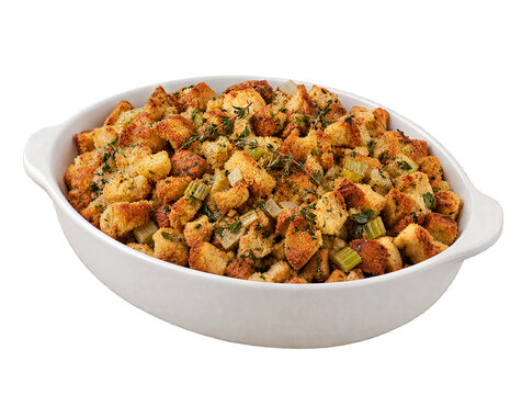 Three-quarter view of homemade bread stuffing with celery and herbs in white baking dish isolated on transparent background.