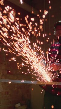 Welder at work in industry, cutting - slow motion. Lots of sparks in factory. Man cuts metal with a angle grinder. Male at a construction site cuts off a piece of metal, fiery sparks and particles fly