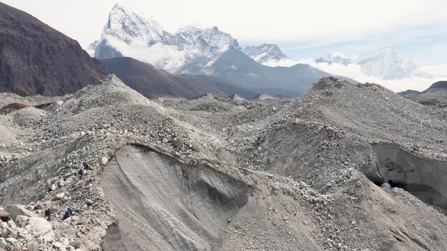 Navigating a dangerous path along a rocky moraine of the khumbu glacier with majestic snow-covered himalayan mountains, including ama dablam in background. A large glacier in the mountains of Nepal.