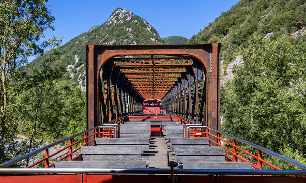 Open tourist train without passengers (Train Rouge) crossing an old truss bridge near the village of Axat (Aude, France) in the Pyrenees