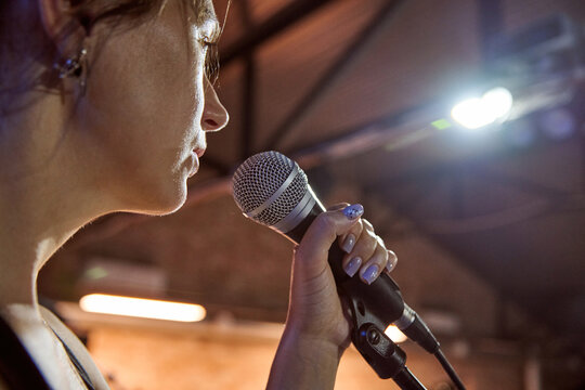Female singer holds microphone during sound check under warm stage lights