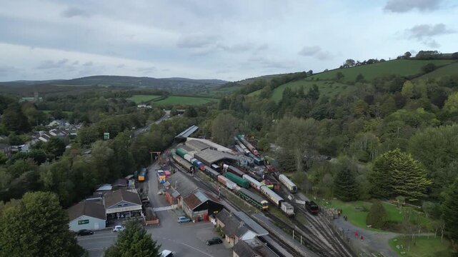 Buckfastleigh, Devon, England: DRONE VIEWS: 1. Stationary steam engines & carriages at Buckfastleigh railway station; 2. Traffic on the Devon Expressway (A38); 3. Buckfast Abbey (background left).