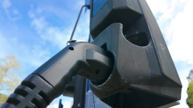 Electric Vehicle Charging Handle Docked in Station Under Blue Sky