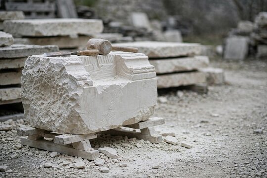 Stone chisel and mallet resting on half carved limestone block