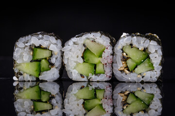 Fresh Cucumber Kappa Maki Sushi Rolls with Sesame Seeds on Reflective Black Background. Gourmet Japanese restaurant menu. Japanese cuisine © dechevm