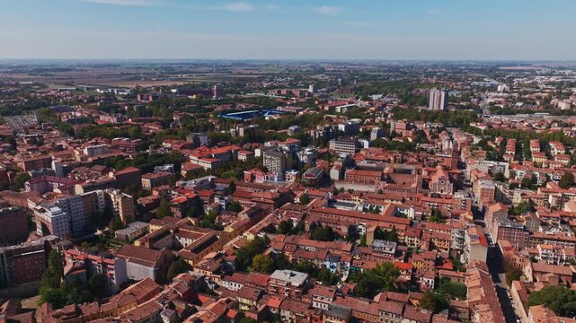 Aerial drone view of Ferrara, Italy, showcasing the historic city center, terracotta rooftops, churches, medieval streets, green spaces, and the Emilia-Romagna cityscape.