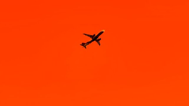 Silhouette of an airplane taking off and gaining altitude in a surreal orange sunset sky over Istanbul. Dramatic contrast, warm light and stylized color grading create an unrealistic evening scene