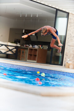 Boy Jumping Into Backyard Pool During Summer Play At Home Vacation