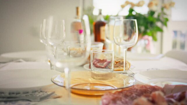 Restaurant-style banquet table in midday sun white plates, appetizers, baked meat and meat skewers, empty glasses gleaming, a clean layout idea for event menus and catering services