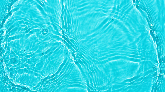 Top down angle of vibrant turquoise water surface with circular ripples under bright lighting