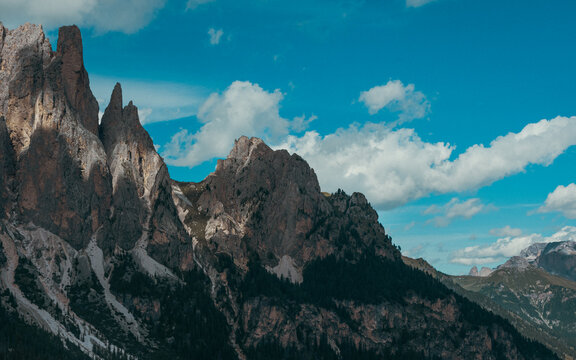 Imponenti pareti rocciose e cime frastagliate sovrastano pendii boscosi, sotto suggestive nubi estive, nei pressi delle Cinque Torri, a Cortina d&rsquo;Ampezzo, nelle Dolomiti venete.