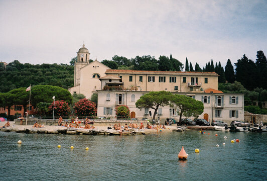 Swimmers and sunbathers gather below a hilltop church