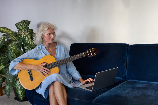 hobby, senior woman learns to play guitar with online tutorial