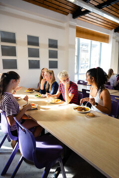 Vertical shot of friends eating in the canteen