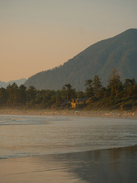 Distant view of people on the sandy beach in Tofino, BC at sunset
