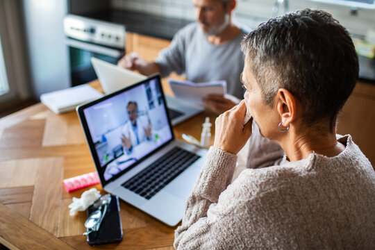 Woman holding tissue during online doctor consultation at home