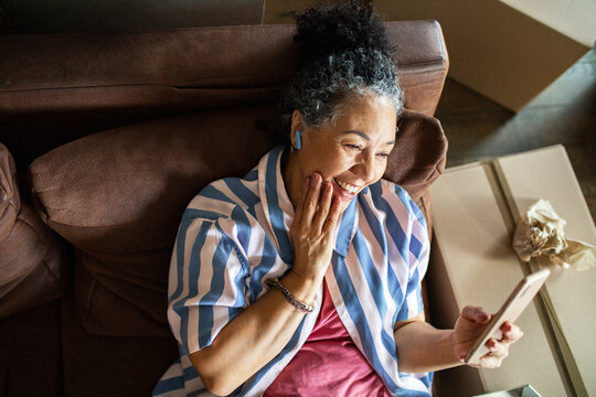 Older woman smiling during video call on smartphone at home