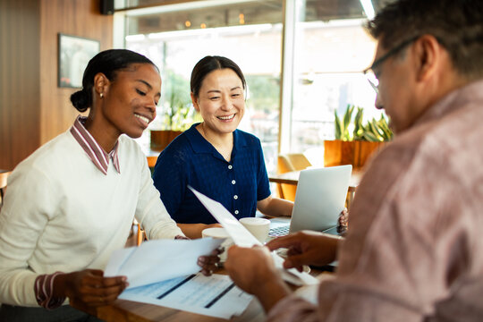 Coworkers reviewing documents over coffee in a cafe