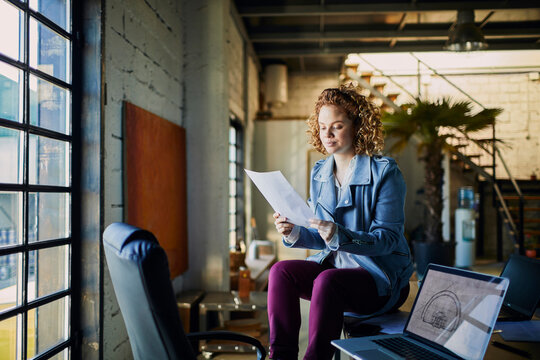 Woman architect reviewing blueprints in loft office