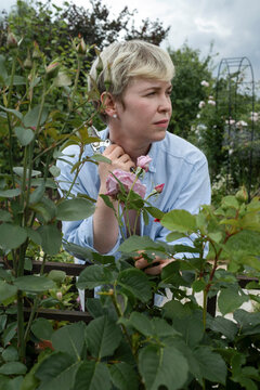 Person stands in a garden surrounded by rose bushes