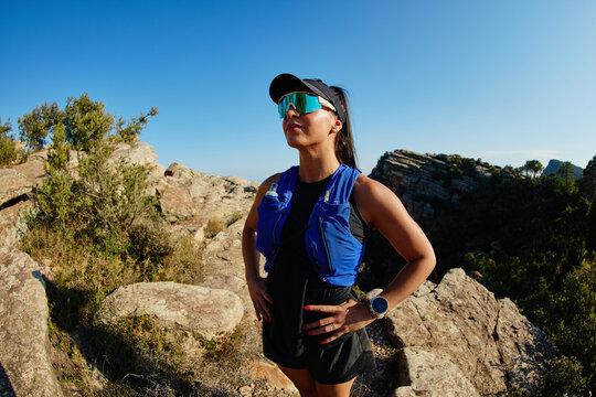 Runner stands on rocky terrain during sunny day