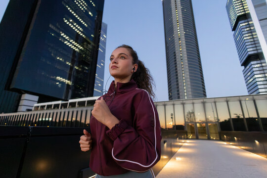 Young woman running in urban city with skyscrapers